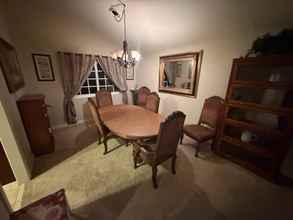 Dining nook with a table, six chairs, bookcases and a mirror before removal