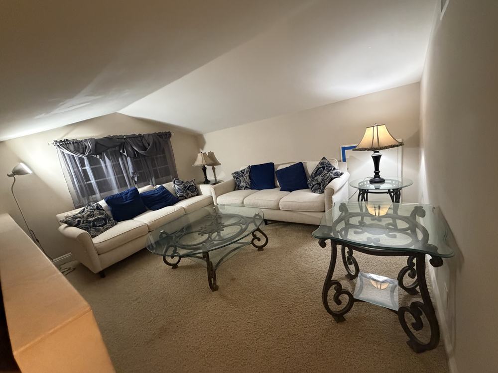 Sitting room with two white sofas, glass tables and lamps before removal